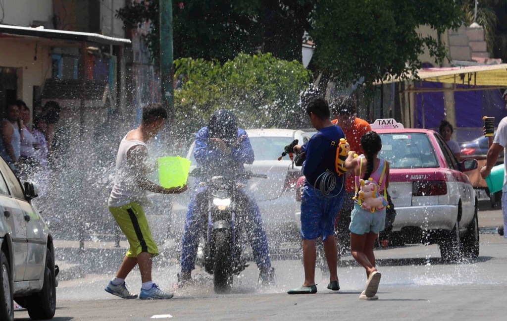 Adolescentes y niños arrojándose agua, antigua tradición de Sábado Santo, en las colonias Guerrero y Morelos de Ciudad de México. La ley prohíbe desperdiciar agua, pero algunas personas lo olvidan