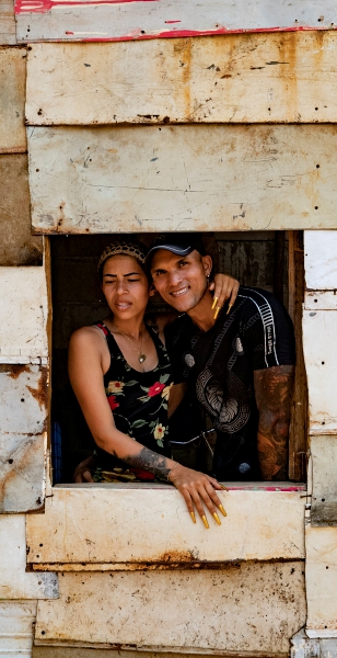 AME109. MATANZAS (CUBA), 19/03/2024.- La joven pareja Gilde (d) y Arianelis (i) se asoman desde una ventana de su casa en una humilde barriada de chabolas junto a la localidad de Santa Marta el 12 de marzo de 2024, en la provincia de Matanzas (Cuba). En medio de la oscuridad de su casa, Catalina, de 35 años, repasa los problemas de su día a día, similares a los que padecen en Cuba millones de personas por la grave crisis económica que sufre el país y que ha generado protestas en varias ciudades en los últimos días. Los apagones, de más de diez horas diarias en muchas provincias, son un calvario para muchos y el detonante -más allá de otras causas profundas- de protestas como las de el pasado domingo. EFE/ Yander Zamora