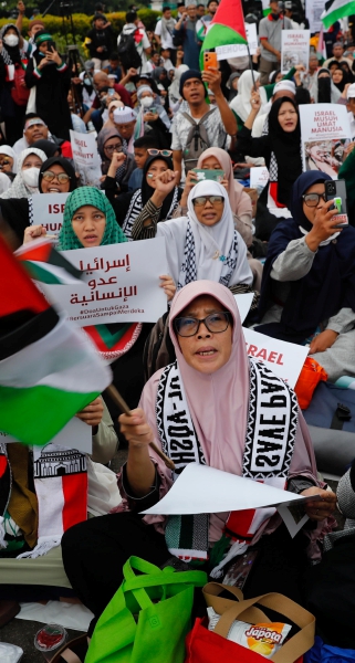 Soldados israelíes en un puesto de control a lo largo de la frontera con Gaza en el sur de Israel. A la izquierda, activistas musulmanes sostienen pancartas que dicen “Humanidad VS Israel” durante una manifestación de solidaridad con los palestinos en Yakarta, Indonesia