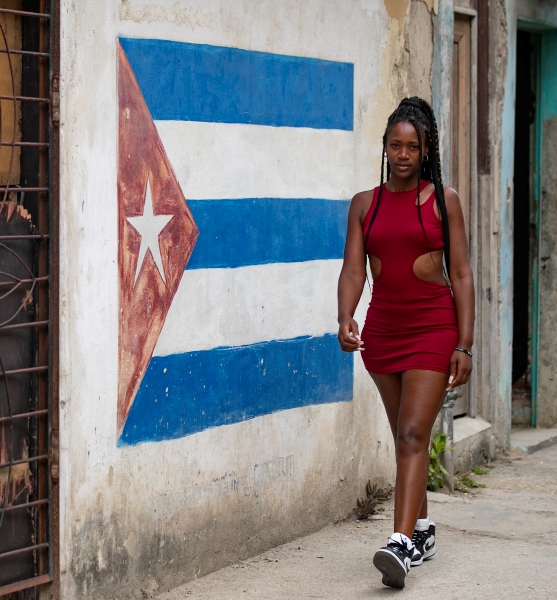 Una joven camina frente a una pared pintada con la bandera cubana en La Habana. Organismos cívicos acusaron a Cuba de violar derechos humanos