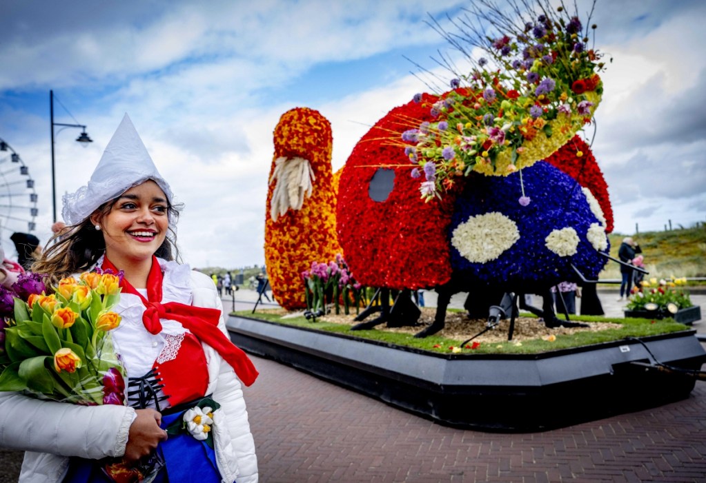 Una joven con traje típico de Países Bajos observa el paso de la carroza del conejo. A la derecha, una florida carroza de osos panda