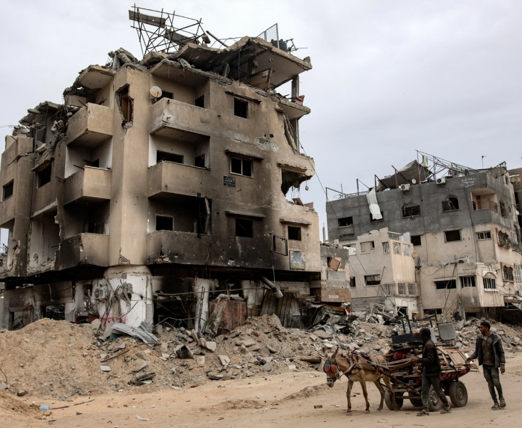 Palestinos conducen un carro por edificios destruidos en Khan Younis, luego que Israel retirara sus fuerzas terrestres del sur de la Franja