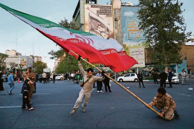 Una persona ondea una bandera iraní en la Plaza Felestín, en Teherán, para celebrar el ataque a Israel