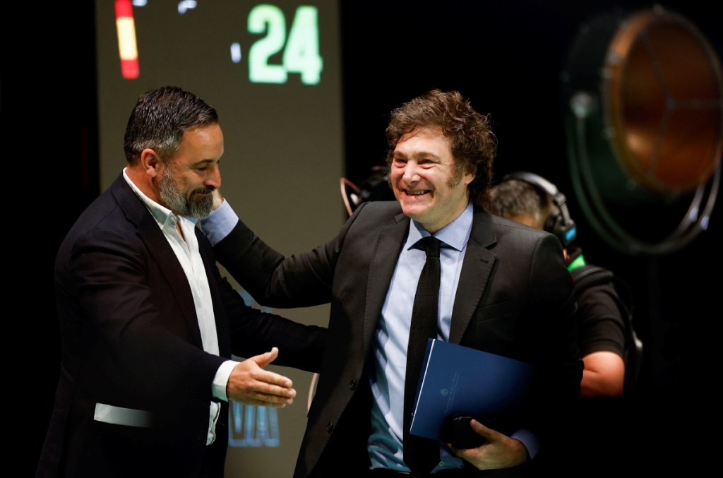 El líder de Vox, Santiago Abascal (izquierda), cede el paso a Javier Milei en la convención de Vox en Madrid