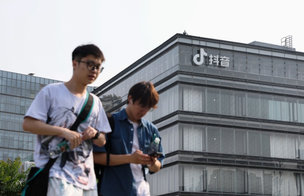 Jóvenes caminan frente a las oficinas de ByteDance, matriz de TikTok, en Pekín, China. Un grupo de “tiktokers” demandó a Estados Unidos