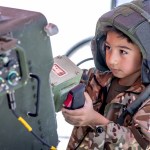 Un visitante sostiene un arma antiaéreas en la “aldea del ejército” durante las celebraciones del fin de semana del Día de los Caídos en Miami Beach. A la izquierda, un niño porta equipo de fuerzas especiales militares mientras lleva un arma