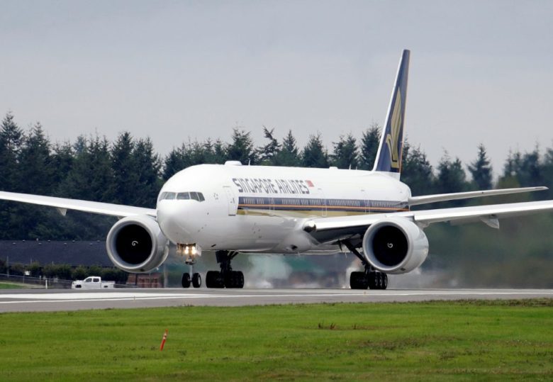 Un avión Boeing 777-312ER de Singapore Airlines se prepara para despegar de Paine Field el martes 17 de septiembre de 2013 en Everett, Washington. A la izquierda, equipos médicos de rescate se preparaban ayer para trasladar a los heridos a un hospital cerca del aeropuerto