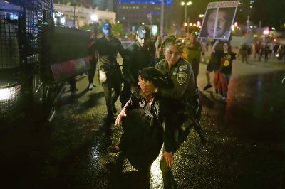 Una mujer policía trata de retirar a una manifestante que bloquea una importante carretera de la ciudad israelí de Tel Aviv, durante la tensa protesta de anoche contra el gobierno de Benjanín Netanyahu