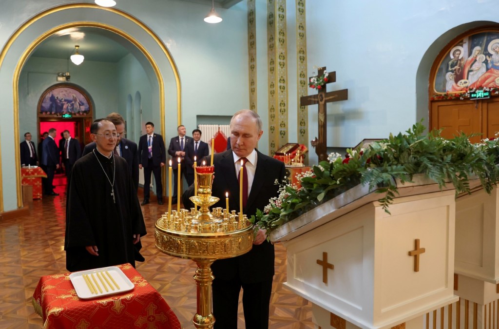 El presidente de Rusia, Vladimir Putin, acompañado por el padre superior Alexander Yu Shi, enciende una vela durante su visita a la Iglesia Ortodoxa de la Intercesión de la Theotokos, en Harbin, Heilongjiang, China