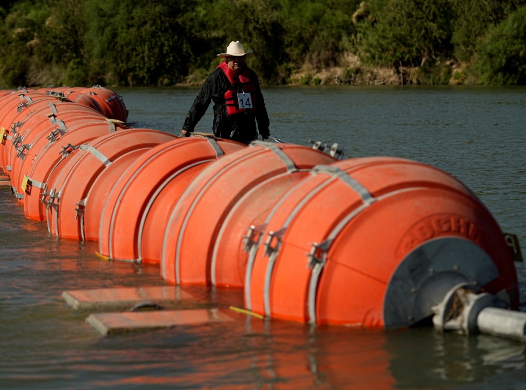 Un kayaquista camina junto a las grandes boyas utilizada como una barrera fronteriza flotante en el río Grande, o Bravo, en Eagle Pass, Texas