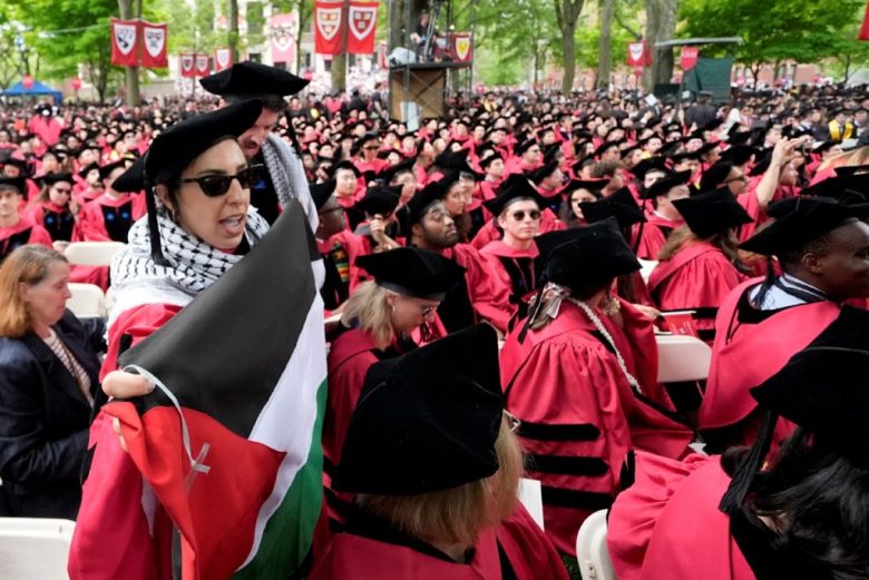 Alumnos gritan consignas al salir de la ceremonia de graduación de la Universidad de Harvard, en protesta contra la sanción a 13 estudiantes, a quienes no se les permitió participar. A la derecha, un estudiante graduado celebra durante la entrega de títulos