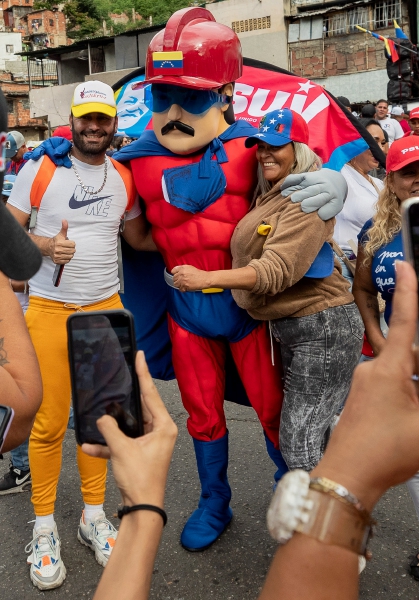 Personas se fotografían con un hombre con el disfraz de Super Bigote durante una marcha chavista en apoyo al presidente de Venezuela Nicolás Maduro