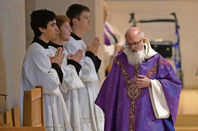 El padre Gabriel Landis oficia una misa en el Benedictine College, en Atchison. A la derecha, Leven Barton, Florian Rumpza y Angelus Atkinson cantan en latín durante la misma misa