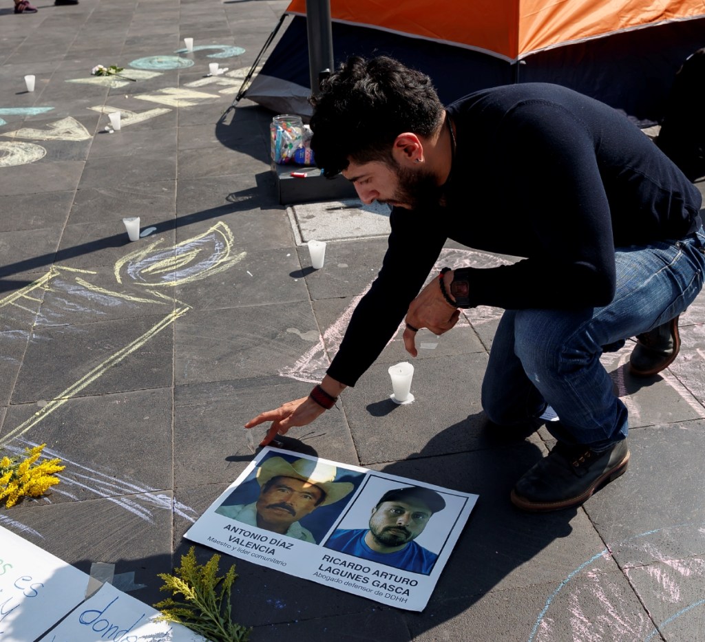 Un hombre pega un cartel con imágenes de los defensores de derechos humanos Antonio Díaz y Ricardo Lagunes, desaparecidos en Aquila