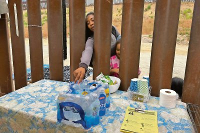 Una mujer intenta tomar una botella de agua en la frontera de San Diego