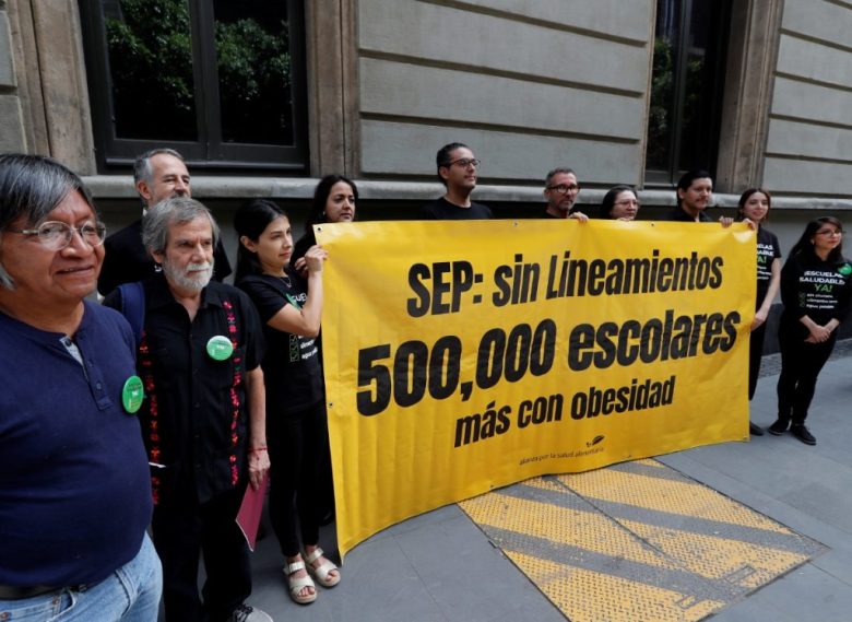 MEX829. CIUDAD DE MÉXICO (MÉXICO), 12/06/2024.- Integrantes de organizaciones civiles sostienen una pancarta durante una protesta al exterior de la Secretaria de Educación Pública (SEP) este miércoles, en Ciudad de México (México). La protesta ante la SEP de México fue para exigir que se aplique la ley en las escuelas para prohibir los alimentos y bebidas no saludables que podrían causar medio millón de casos de obesidad infantil en un año. EFE/ Mario Guzmán