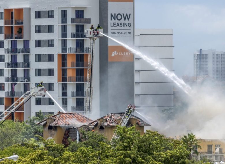 Bomberos y policías de Miami trabajan para extinguir un incendio en el edificio de departamentos Temple Court Apartments. A la izquierda, otro aspecto de las labores de los bomberos, según los cuales, unas 40 personas fueron rescatadas del edificio, que albergaba principalmente a residentes de edad avanzada