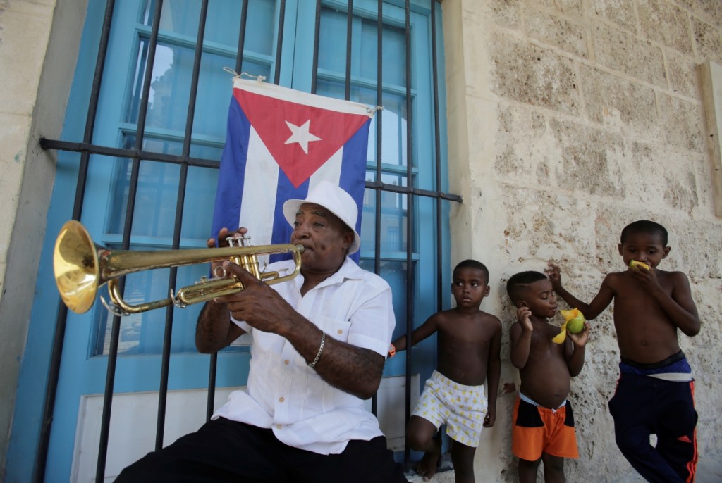 Carlos Masa usa una guayabera mientras toca la trompeta para pedir propinas a los peatones en La Habana, Cuba, el domingo pasado. A la derecha, el actor estadounidense Johnny Deep, durante la premier de la película “Piratas del Caribe” en Londres, Inglaterra, en 2006