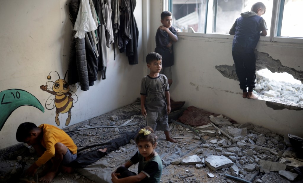 Niños palestinos observan los daños en una escuela que da refugio a personas desplazadas, un día después de que una casa cercana fue atacada por bombas israelíes en Jan Yunis, en el sur de la Franja de Gaza