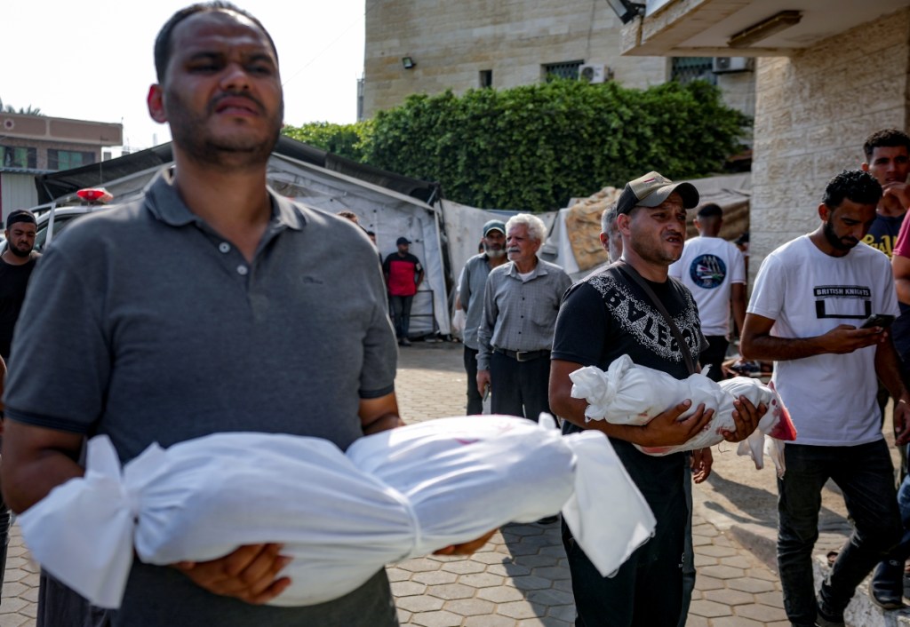 Palestinos cargan cuerpos de niños muertos tras los bombardeos en un hospital de Deir Al-Balah, ayer