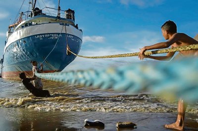 Niños juegan con las cuerdas de un barco atracado en una playa de Parika, Guyana, Cuba, en junio pasado