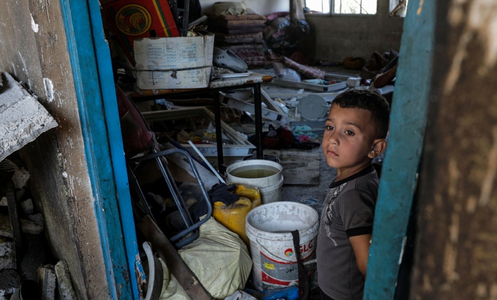 Un pequeño palestino observa los daños en una escuela, tras ataque realizado a un campo de refugiados