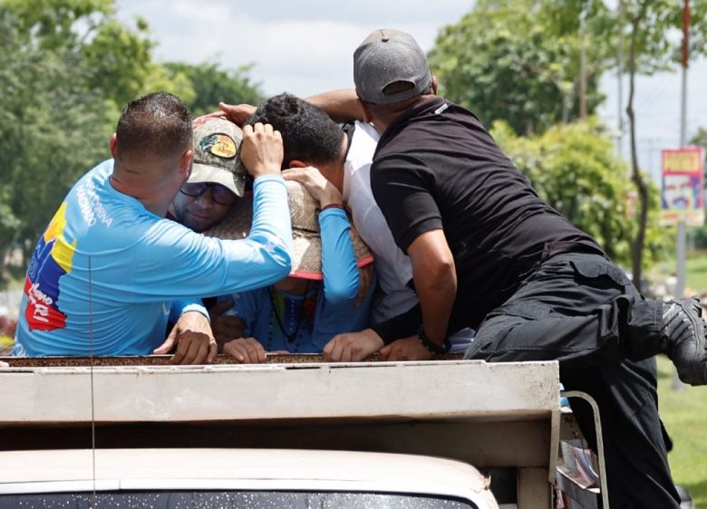 Guardias protegen a María Corina Machado mientras simpatizantes de Nicolás Maduro le lanzan huevos, ayer en Maturín