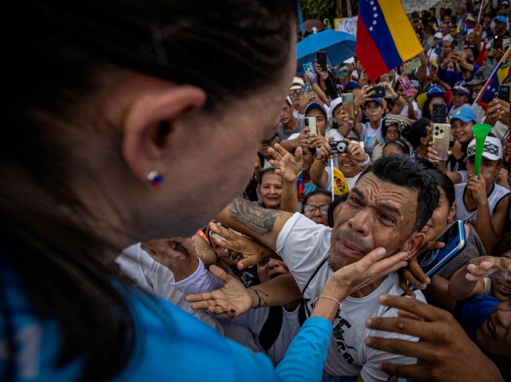 La líder antichavista María Corina Machado saluda a simpatizantes durante una caravana en Maturín, Venezuela. A la derecha, el presidente venezolano y candidato a reelegise, Nicolás Maduro, durante un mitin de campaña en el barrio Catia de Caracas