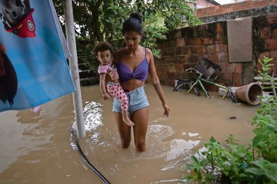 Una joven camina entre el agua tras una inundación en Rio de Janeiro en 2023. El agua estancada aumenta el brote de mosquitos