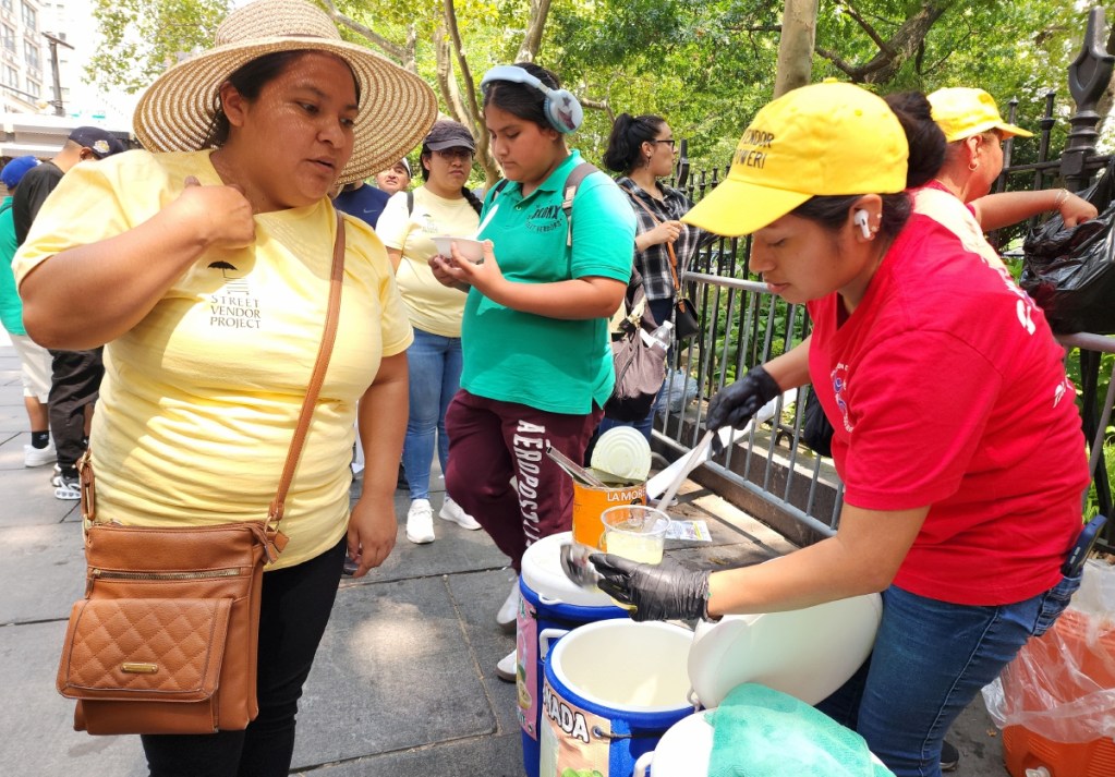 Mujeres reparten comida al final de una protesta de ambulantes, frente a la Alcaldía de Nueva York