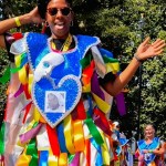 Con coloridos trajes, integrantes de una comparsa se disponen a iniciar el desfile. A la derecha, membros de “Urban Troup” se preparan para participar