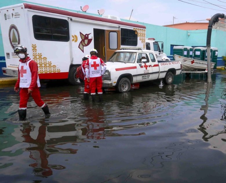 Hombres utilizan una balsa para auxiliar a una mujer que quedó atrapada en las calles inundadas de Chalco, Estado de México