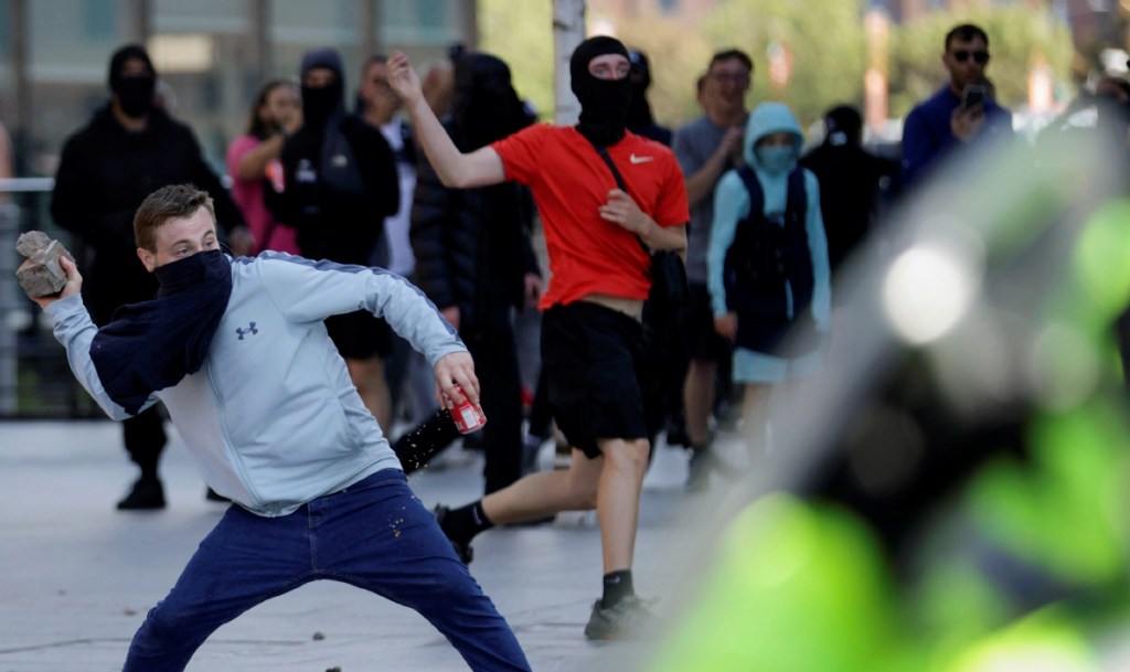 Un manifestante lanza un ladrillo durante la protesta del sábado en Liverpool, que la policía tuvo que contener de manera violenta