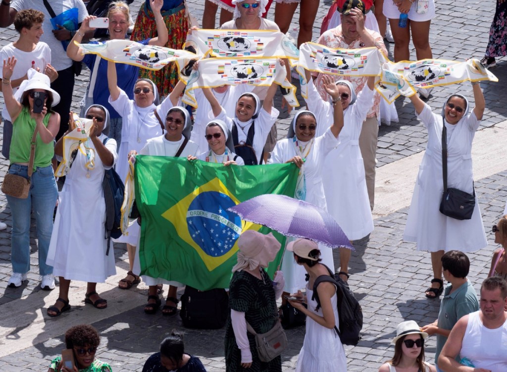 Imagen proporcionada por Vatican Media muestra a jóvenes franciscanos sosteniendo una bandera ucraniana mientras escuchan el Ángelus del papa Francisco en la Plaza de San Pedro, en Ciudad del Vaticano. A la izquierda, religiosas brasileñas agitan banderas para llamar la atención del pontífice