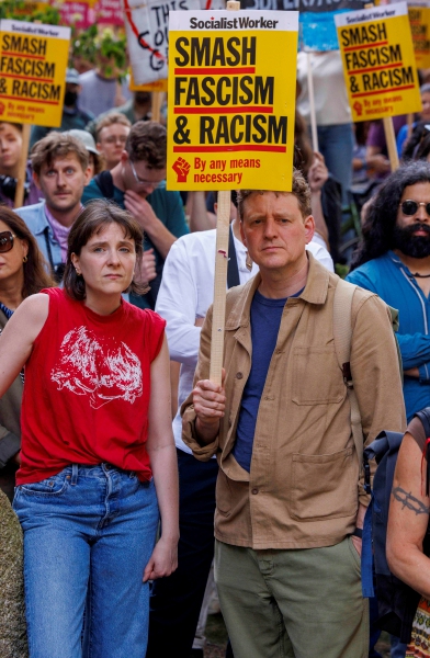 Sobre estas líneas, un contingente de manifestantes protesta contra el controvertido líder del partido Reform UK, Nigel Paul Farage , durante la marcha de ayer en Londres. A la izquierda, una mujer con un cartel que dice “¿Por qué todavía me juzgas por el color de mi piel?”