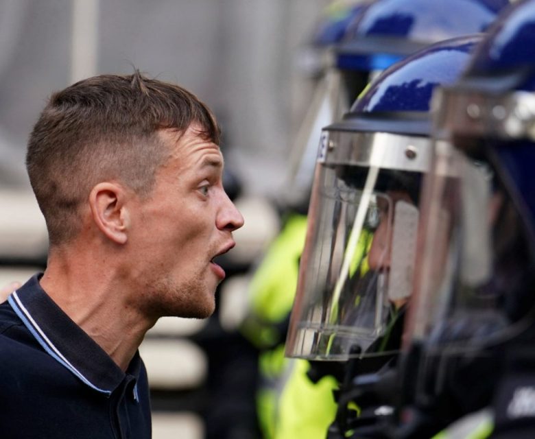 Un manifestante confronta a un oficial de policía durante una protesta que tuvo lugar ayer en Whitehall, Londres, bajo el lema de ”Basta ya” por el homicide de las tres niñas de Southport. A la derecha, los agentes intentan controlar a la multitud enfurecida en la manifestación de Whitehall, ayer por la mañana