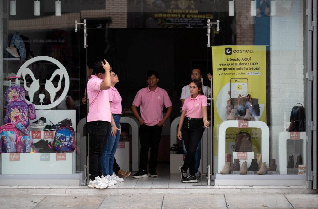 Empleados de una tienda comercial de Caracas esperan frente al establecimiento a que regrese el servicio eléctrico, durante el apagón que afectó ayer varias horas la capital de Venezuela y otras ciudades del país