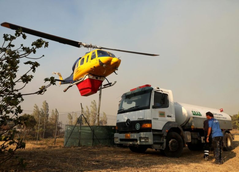 Un helicóptero llena su depósito de agua en la villa de Penteli