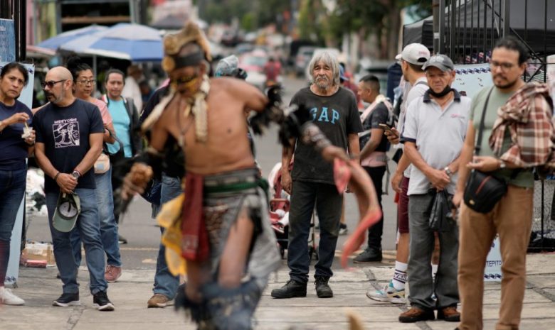 La gente observa a los danzantes mientras conmemoran el 503 aniversario de la caída de la capital del imperio azteca, Tenochtitlán, en la Ciudad de México, el martes 13 de agosto de 2024. (AP Foto/Eduardo Verdugo)