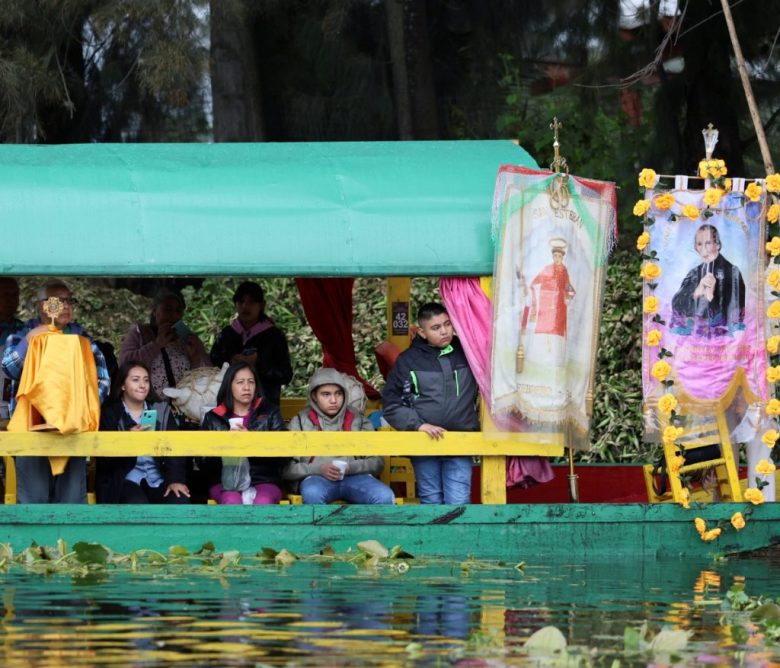 Los devotos observan cómo se transporta una reliquia de San Judas Tadeo en una urna a través de los canales de Xochimilco, Ciudad de México, el domingo 11 de agosto de 2024. (AP Foto/Ginnette Riquelme)