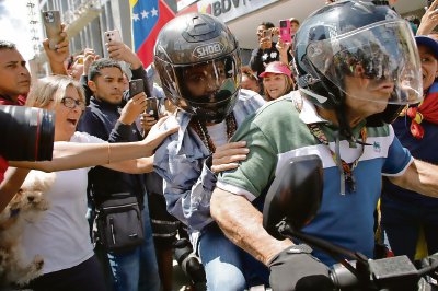 La líder opositora María Corina Machado se marcha de la protesta a bordo de una motocicleta ante la algarabía de sus seguidores