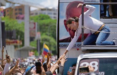 María Corina Machado, la líder opositora, saluda a sus partidarios durante la masiva manifestación de ayer en Caracas. A la derecha, una persona disfrazada del presidente de Venezuela, Nicolás Maduro, participa en la manifestación oficialista que se llevó a cabo en la capital del país