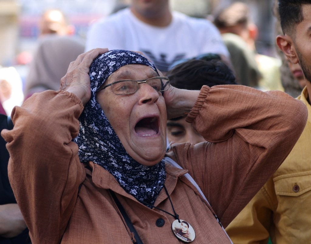 Una mujer llora mientras palestinos asisten a una marcha tras un ataque israelí a una escuela en Gaza