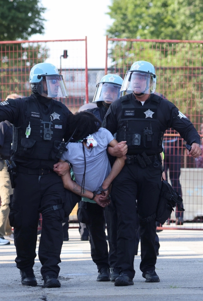 Policías detienen a manifestantes que violaron la valla perimetral en la noche inaugural de la Convención Nacional Demócrata en Chicago. A la izquierda, aspecto de la protesta
