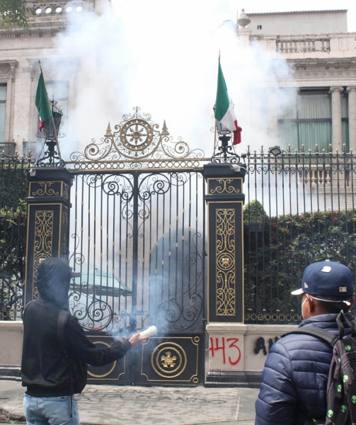 A la derecha, un estudiante hace una pinta con aerosol en una barda de la Secretaría de Gobernación en Ciudad de México, donde ayer normalistas de varias escuelas se manifestaron por el caso de los 43 desaparecidos