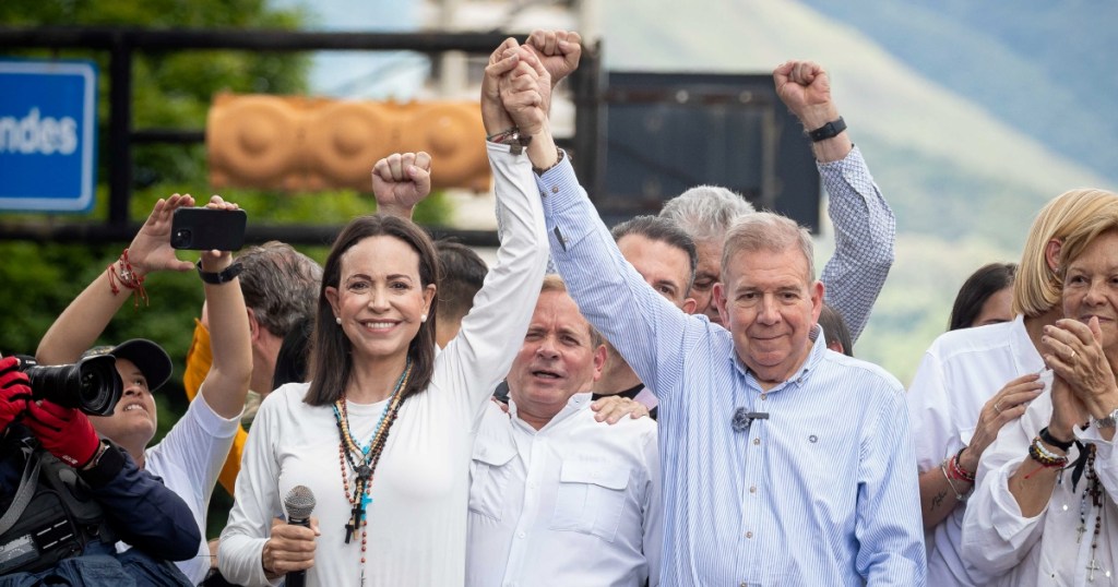 La líder opositora venezolana María Corina Machado levanta la mano al candidato a la presidencia Edmundo González Urrutia durante una protesta, en Caracas, el 30 de julio