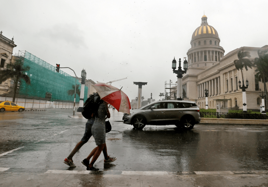 Peatones caminan bajo la lluvia en La Habana. Las autoridades cubanas reportaron 12,000 casos sospechosos de oropouche
