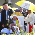 El papa Francisco bendice a los fieles durante una misa en la explanada de Taci Tolu, en Dili, Timor Oriental. A la derecha, un asistente sostiene figuras religiosas durante una misa oficiada por el Papa