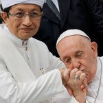 El papa Francisco besa la mano del gran imán de la mezquita Istiqlal, Nasaruddin Umar, tras un encuentro con líderes religiosos en Yakarta. A la derecha, escenario preparado para la santa misa