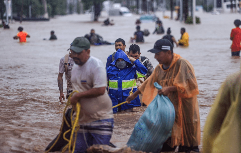 Damnificados cruzan una avenida inundada por el paso del huracán “John” en la parte alta del puerto de Acapulco. Las autoridades reportaron 18 muertos en Guerrero, cinco en Oaxaca y uno en Michoacán